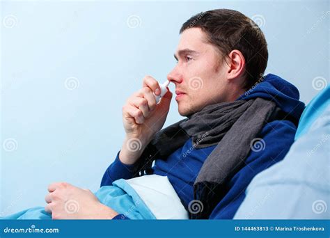 Side Photo Of Sick Brunet Male Using Nasal Spray While Lying In Bed