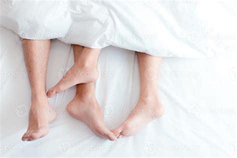 Closeup Feet Of Couple On The Bed Man And Woman Lovers Make Love Under The Blanket Or Bed Sheet