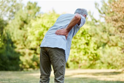 La Mujer Ayuda Al Viejo Hombre Con Dolor De Espalda Foto De Archivo