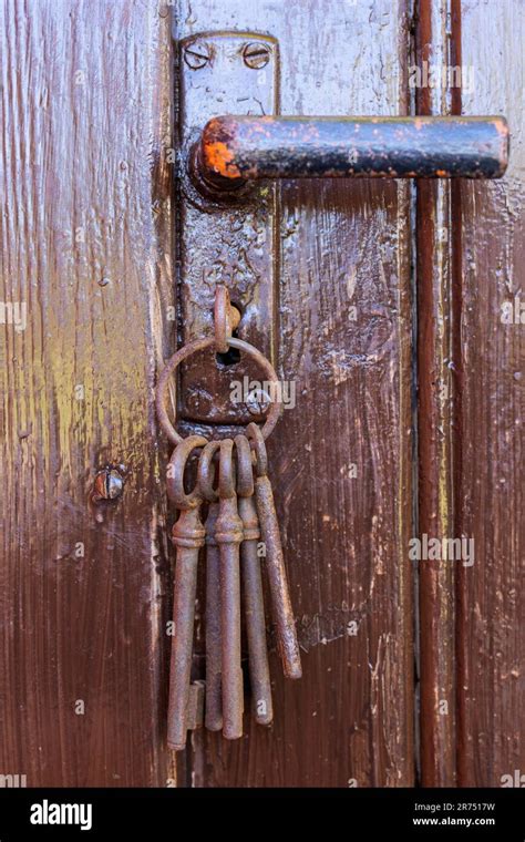 Old rusty key in the keyhole of a brown wooden door Stock Photo - Alamy
