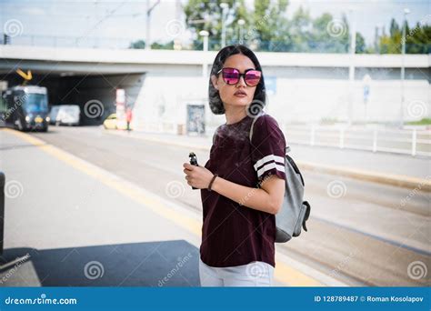 Pretty Brunette Woman Smoking An E Cigarette Standing In A Street Exhaling A Cloud A Smoke From
