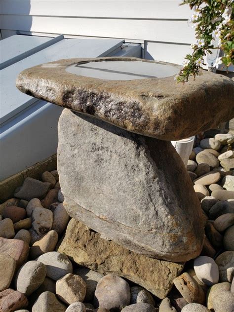 A Rock Sitting On Top Of A Pile Of Rocks Next To A White Building With