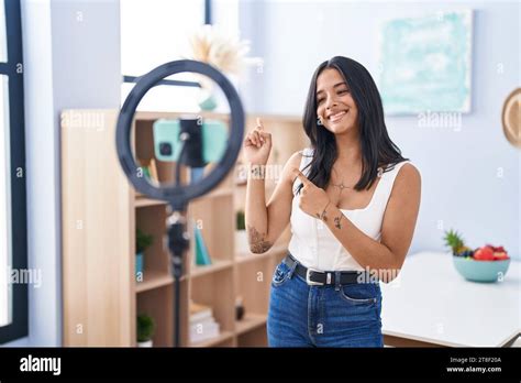 Brunette Woman Recording Vlog Tutorial With Smartphone At Home Smiling And Looking At The Camera