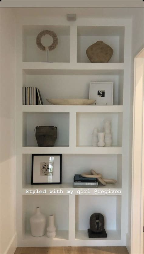 A White Book Shelf Filled With Lots Of Books And Vases On Top Of It