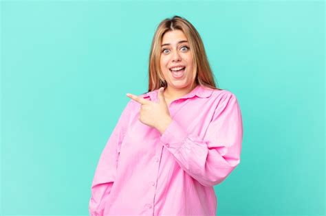 Premium Photo Curvy Pretty Blonde Woman Looking Excited And Surprised Pointing To The Side