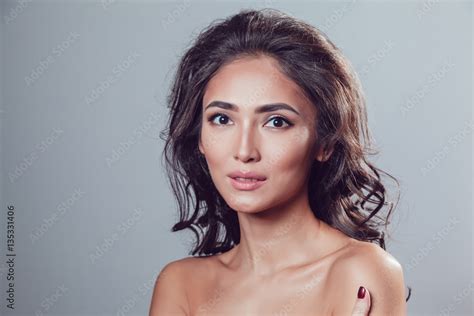 Brunette Girl With Shiny Wavy Hair And Beautiful Make Up Posing At Studio On Grey Background