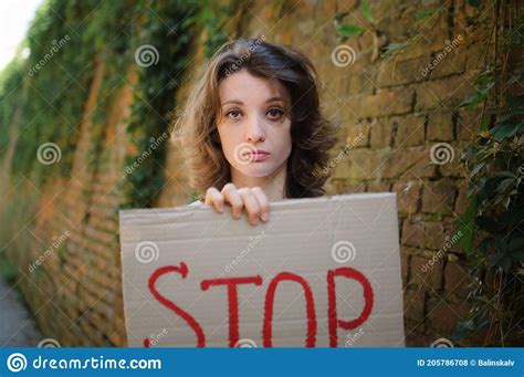 Young Protesting Woman In White Shirt And Jeans Holds Protest Sign