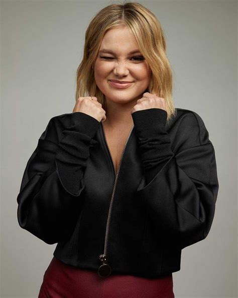 A Woman In A Black Jacket And Red Skirt Posing For The Camera With Her