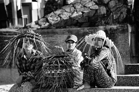 Premium Photo Women Sitting On Steps With Stack Of Palm Leaf Hats