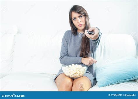 Young Woman Eating Popcorn While Watching Tv At Home Stock Image