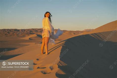 Naked Female Posing On A Sand Dune Wrapped In White Cloth SuperStock