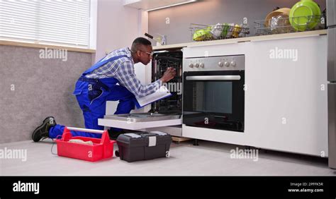 African American Repairman Fixing Dishwasher Appliance Machine Stock