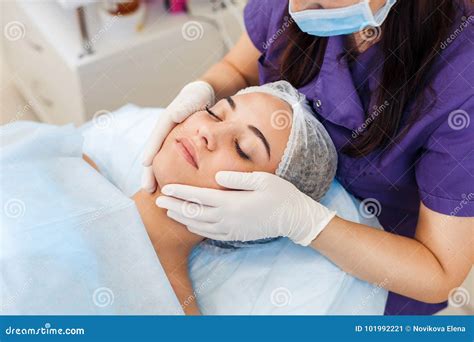 Cosmetologist In Gloves And Medical Mask Applying Cream To The Face And