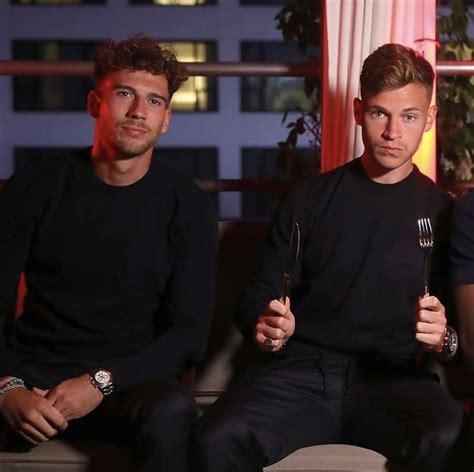 Two Men Sitting On A Couch With Forks In Their Hands And One Holding A Fork