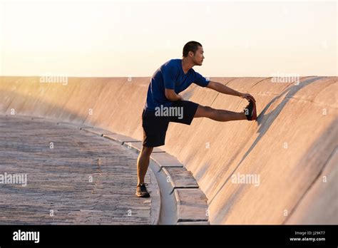 Athletic Young Asian Man Stretching His Legs Before A Run Stock Photo