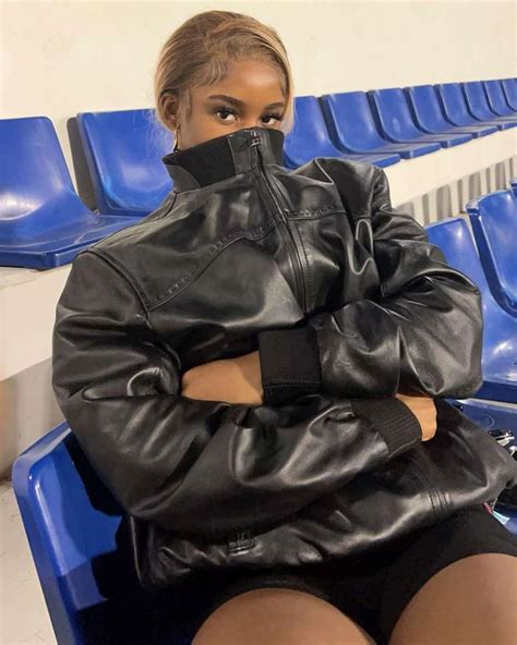 A Woman Wearing A Black Leather Jacket Sitting On A Blue Bench With Her