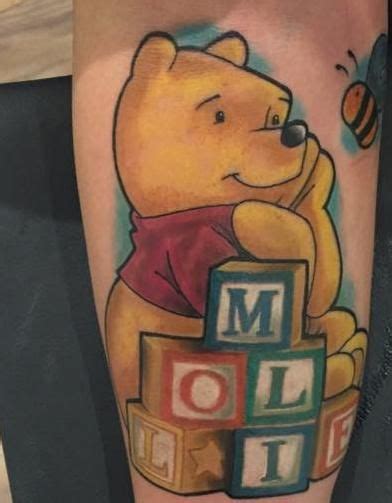 Winnie The Pooh Tattoo With Blocks And A Bee On His Arm That Says Moolai