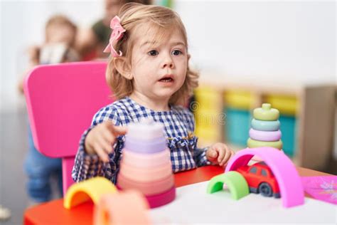 Adorable Hispanic Girl Playing With Hoops Game Sitting On Table At