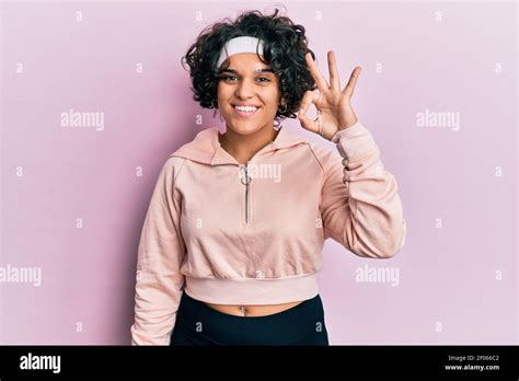 Young Hispanic Woman With Curly Hair Wearing Sportswear Smiling