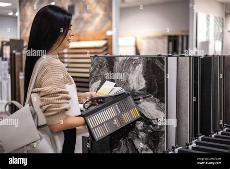 Happy Brunette Female Interior Designer Choosing Flooring Tile Color Texture Samples At Store