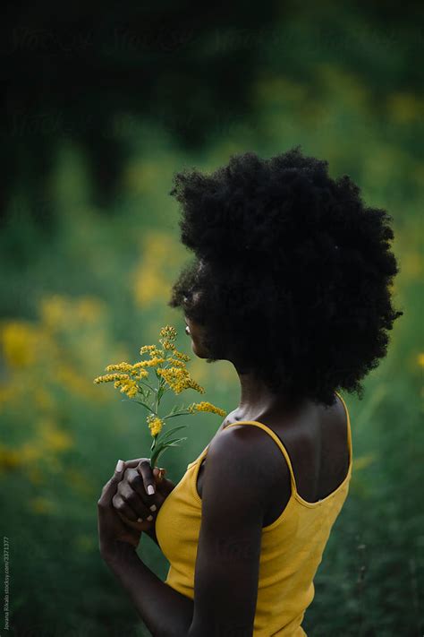 Portrait Of A Young Black Woman In A Yellow Flower Field By Stocksy