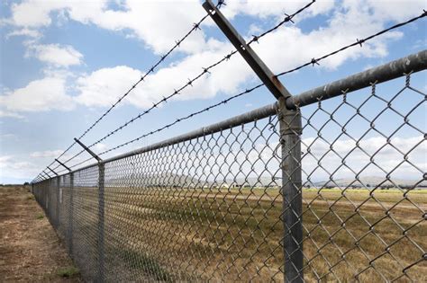 A Long Chain Link Fence With Barbed Wire Stretches Into Istance Stock Image Image Of Defense