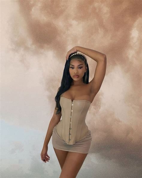 A Woman Wearing A Corset And Posing For A Photo With Clouds In The