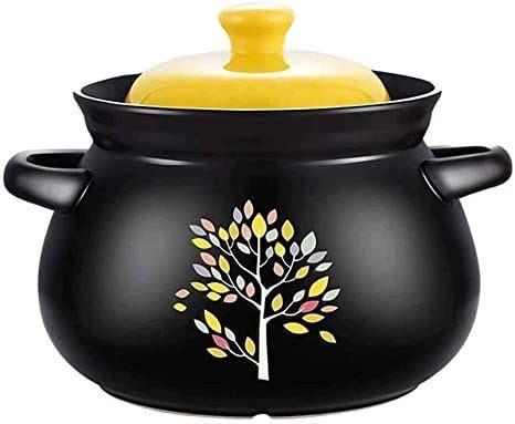 a black pot with a yellow lid and a tree painted on the side, is shown