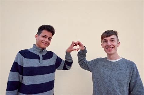 Una joven pareja gay interracial formando un corazón con sus manos aisladas sobre un fondo beige