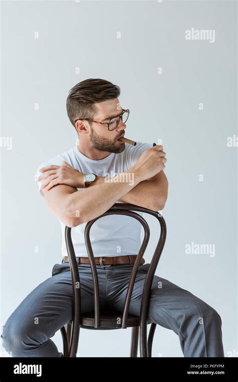 Handsome Bearded Man Lighting His Cigar While Sitting On Chair Isolated On White Background