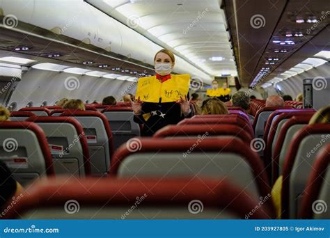 Stewardess In A Mask Demonstrates To Aircraft Passengers The Rules Of