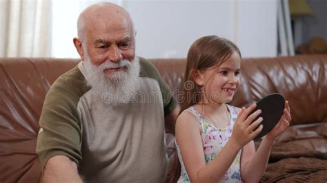 Smiling Old Grandfather Combing Braiding Hair Of Granddaughter Talking