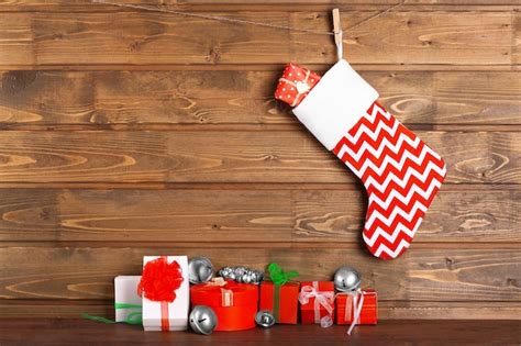 Premium Photo Christmas Stocking And Presents Against Wooden Wall