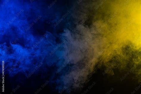 Yellow-blue smoke in neon light on black background. Stock Photo ...