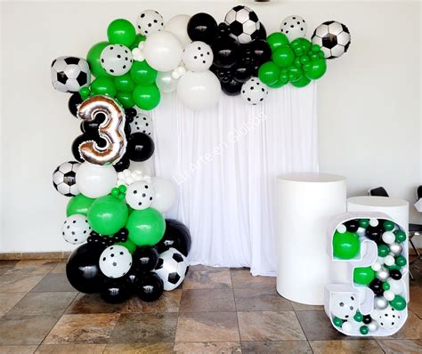 The Balloon Arch Is Decorated With Black White And Green Soccer Balls