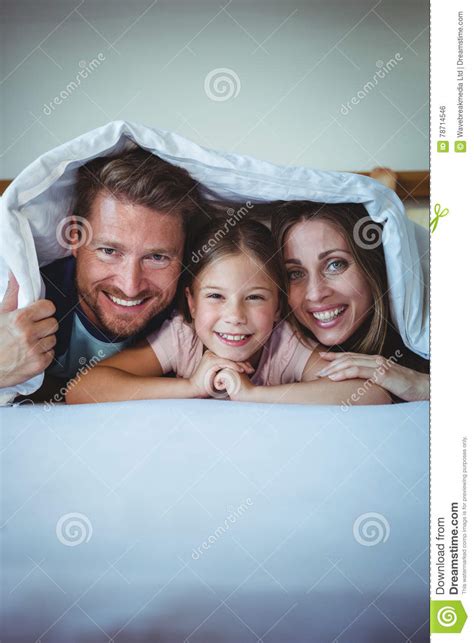 Familia Feliz Que Miente Debajo De Una Manta En Cama Foto De Archivo