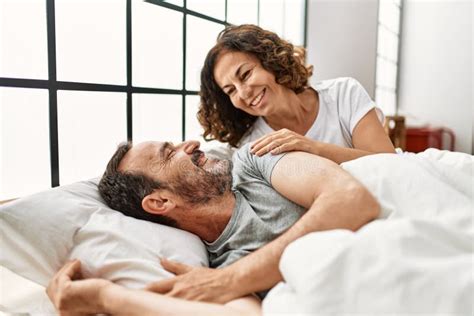 Middle Age Hispanic Woman Waking Up Her Husband Lying On The Bed At Home Stock Image Image Of