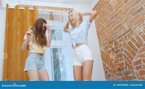 Two Young Happy Girlfriends Jumping On Bed And Having Fun Stock