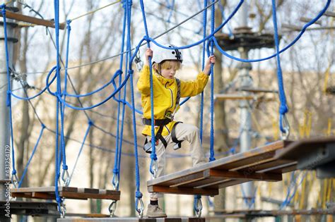 Little boy having fun in Adventure Park for children amoung ropes ...