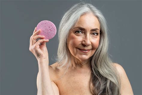 Premium Photo Smiling Retired European Naked Female With Gray Hair Shows Massage Sponge For Face