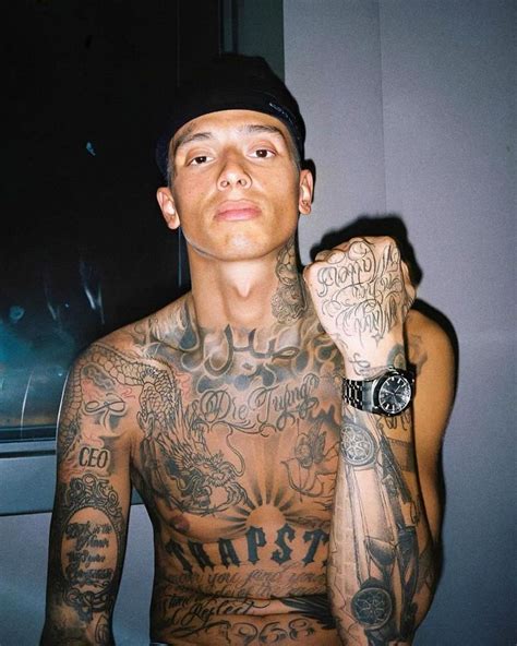 A Man With Lots Of Tattoos On His Chest And Arm Is Posing For The Camera