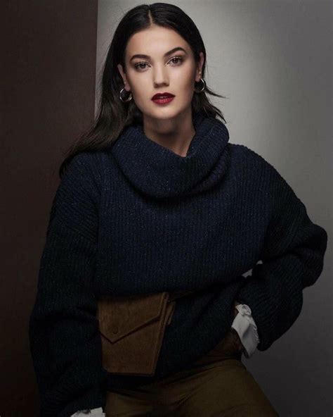 A Woman Sitting On Top Of A Chair Wearing A Black Sweater And Khaki Pants