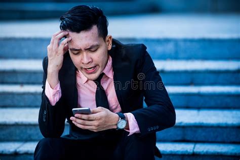 Stressed And Angry Asian Businessman Looking At Smartphone Screen With