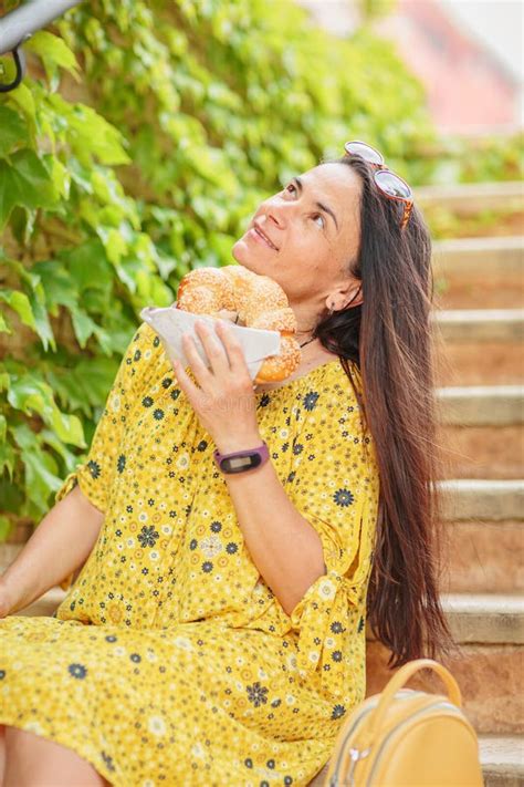 Attractive Brunette Woman Sitting On Stairs With Bagel Stock Photo Image Of Biting Cheerful