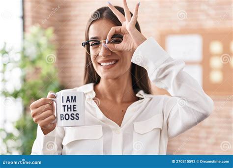 Young Brunette Woman Drinking From I Am The Boss Coffee Cup Smiling