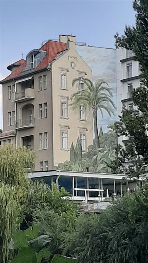 A Building With A Mural On It S Side Next To Some Trees And Bushes