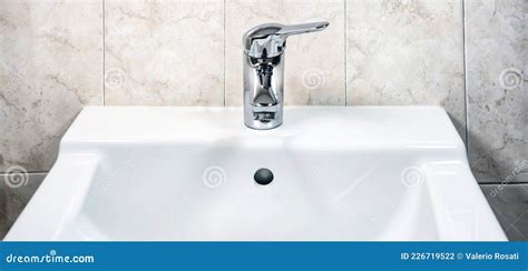 Chromed Faucet With Lever To Mix Hot And Cold Water On A Modern White Sink In A Bathroo Stock
