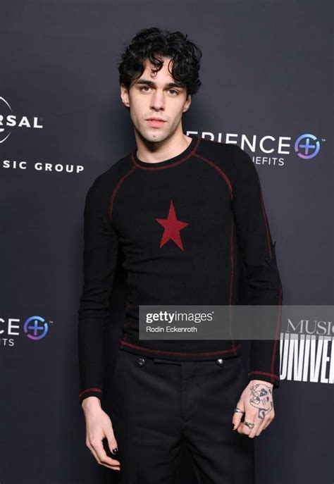 an image of a man in black and red shirt posing for the camera on a red ...