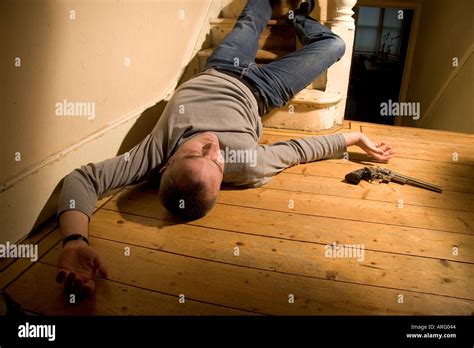 Body Of Dead Man Lying On The Floor At The Bottom Of Stairs With A