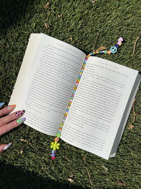 A Person Is Holding An Open Book In Their Hand On The Grass With